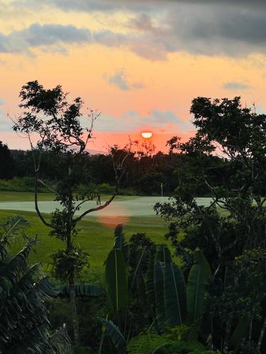 a sunset over a field with a river and trees at Private Secluded Cosy Studio in Avalon Golf Estate in Bois Chéri