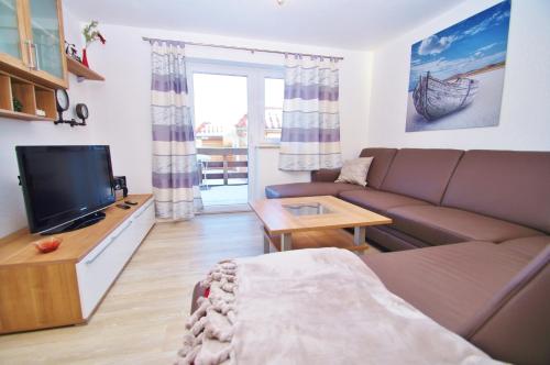Una sala de estar con un sofá y un televisor. en Ferienhaus Timm, en Kellenhusen