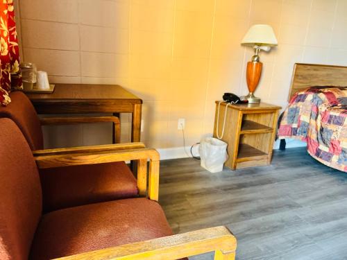 a room with a bed and a chair and a lamp at Clayton House Motel in Loves Park