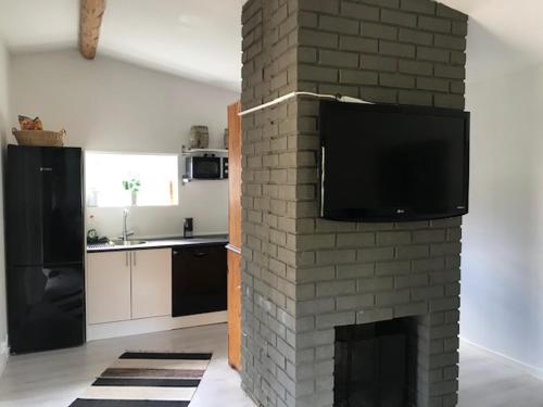 ein Wohnzimmer mit einem gemauerten Kamin und einem Flachbild-TV in der Unterkunft Lillhuset Värmdö in Herrviksnäs