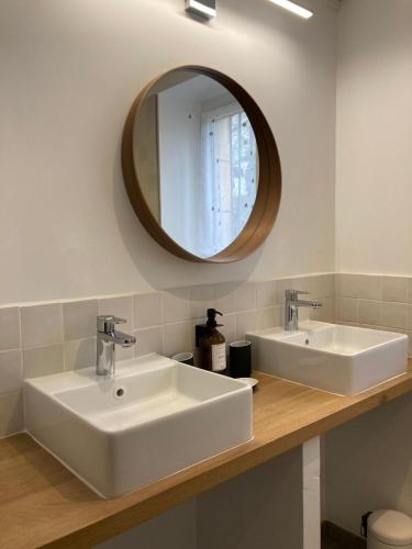 une salle de bain avec deux lavabos blancs et un miroir dans l'établissement Le Jardin de Marie - la maison d'hôtes Sancerre, à Neuilly-en-Sancerre