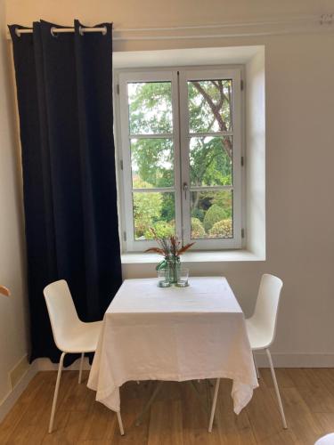 un tavolo da pranzo con sedie e una finestra di Le Jardin de Marie - la maison d'hôtes Sancerre a Neuilly-en-Sancerre