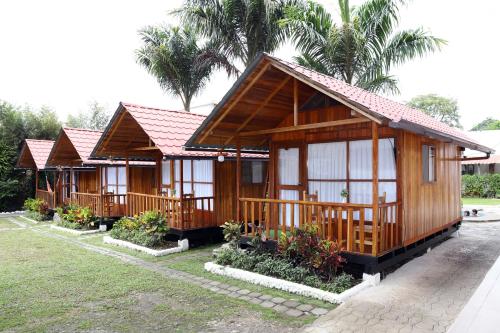 a row of wooden cottages with palm trees in the background at La Posada de Mindo in Mindo