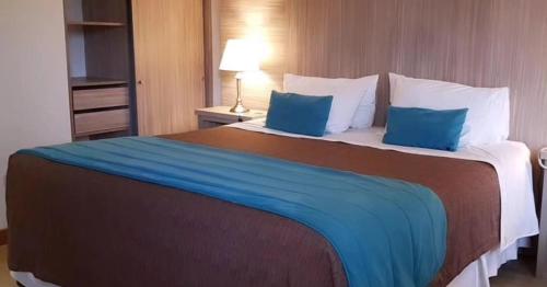 a large bed in a hotel room with blue pillows at Hotel D&V Concepción in Concepción