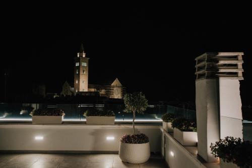 a balcony with potted plants and a clock tower at night at Marcone Luxury Rooms - Il giardino di pietra in Trani