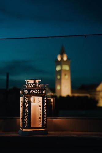 a candle with a clock tower in the background at Marcone Luxury Rooms - Il giardino di pietra in Trani