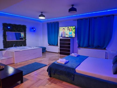 a bedroom with a bed and a tv and blue lighting at RIS Studio premium lux jacuzzi in Bucharest