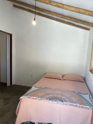 a bedroom with a bed with a pink bedspread at Raizes da Terra - Ponta do Corumbau in Corumbau