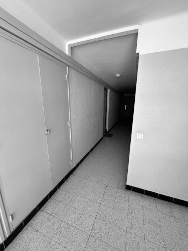 un couloir vide avec des murs blancs et du carrelage dans l'établissement EStudio 1ère ligne vue mer ,place de parking privée accès a la plage de la résidence 3ème étage, à Palavas-les-Flots