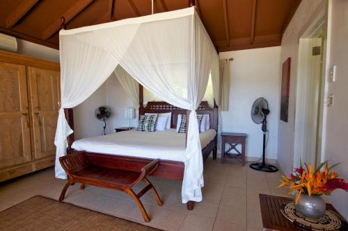 Reef Resort Vava'u في Utungake: غرفة نوم بسرير مظلة وكرسي