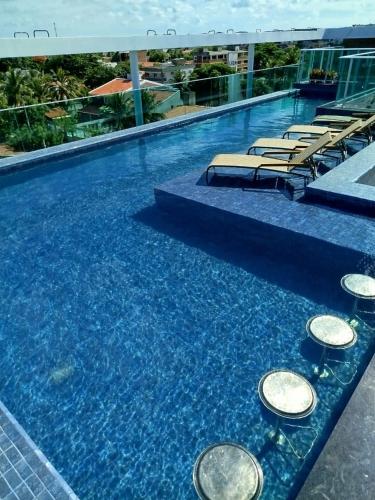 a swimming pool with chairs and blue water at Hoa Beach in Tamandaré