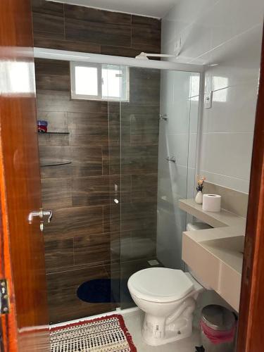 a bathroom with a toilet and a glass shower at Casa de praia PB in Pitimbu