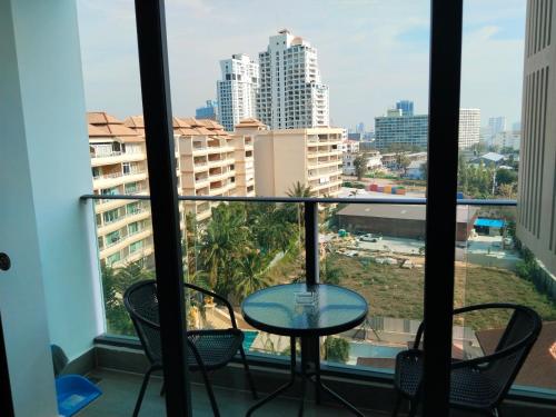 a balcony with a table and chairs and a view of the city at Cozy Beach & Pra Tamnak Condo Pattaya in Pattaya South