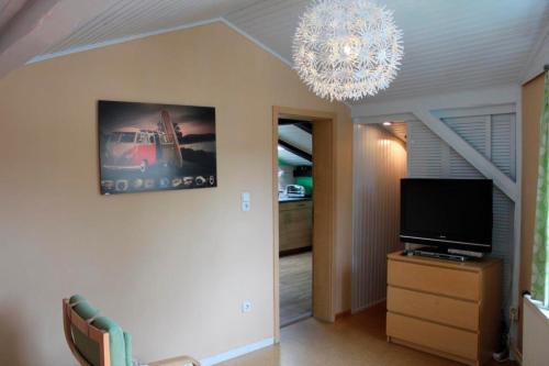 a living room with a television and a chandelier at Ferienwohnung Carstensen Nr2 in Fehmarn