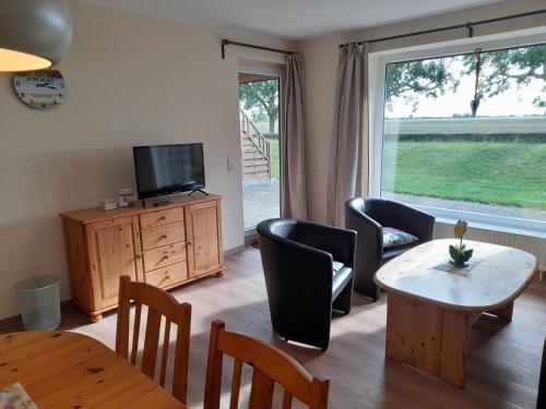 a living room with a table and chairs and a television at "Höper Mittelhof" Ferienhaus Nr3 in Lemkendorf