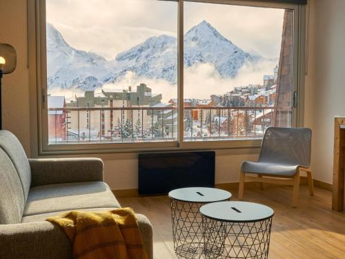 - un salon avec un canapé, une chaise et une grande fenêtre dans l'établissement Grand studio rénové au pied des pistes - FR-1-546-39, à Les Deux Alpes