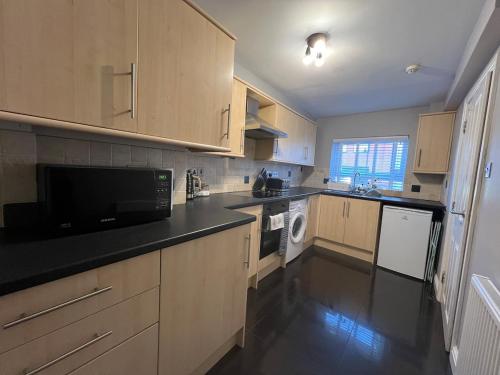 a kitchen with wooden cabinets and a black counter top at 2 bedroom central apartment in Hereford