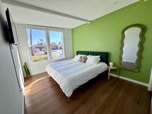 a green bedroom with a bed and a mirror at 4 Bed Modern Pool House with Spa & Game Room in Northridge Hospital Heliport