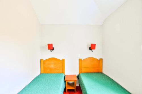 - 2 lits dans une chambre blanche avec des draps verts dans l'établissement La résidence du Lac - maeva Home - Maison 3 pièces 6 personnes - Sélection MAE-3941, à Monflanquin