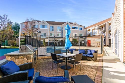 a patio with a table and chairs and an umbrella at Avia Residences on Research - Extended Stay in Westborough