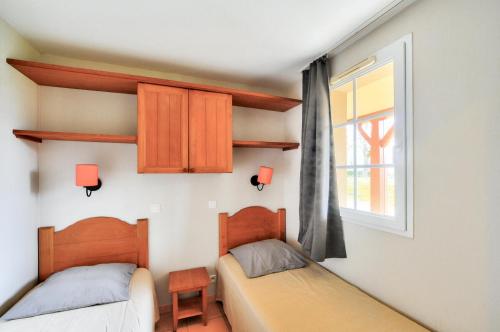deux lits dans une chambre avec une fenêtre dans l'établissement La résidence du Lac - maeva Home - Appartement 2 pièces 4 personnes - Sélection MAE-5781, à Monflanquin
