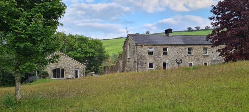 an old stone building on a hill next to a field at The Old Mill, Argideen River Lodges in Timoleague