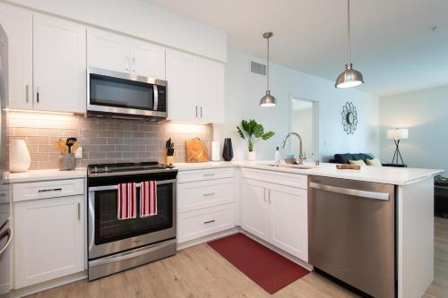 a kitchen with white cabinets and stainless steel appliances at Chic 3-bed Apt with Pool & Hot Tub in Heart of DTLA in Los Angeles