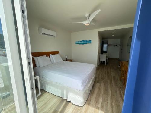 a bedroom with a white bed with a ceiling fan at Seaview Beach Hotel in Philipsburg