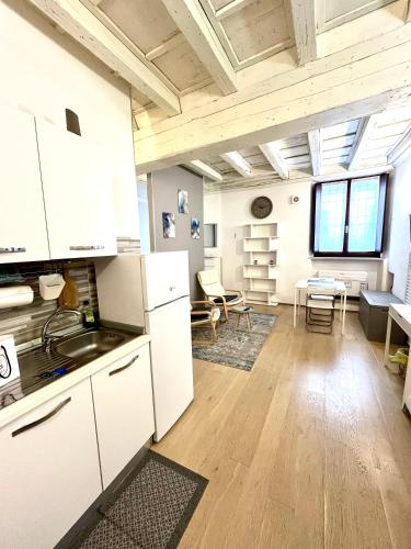 Una cocina con gabinetes blancos y una sala de estar. en RESIDENZA SERENA SUITE-Centro Storico, en Mantua