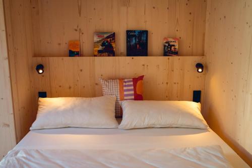 a bed in a wooden room with two pillows at Exklusive Cabins am Rursee inmitten der Natur – mlab relax Eifel in Simmerath