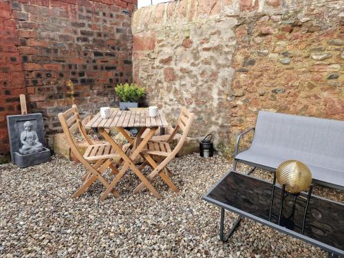 a patio with a table and chairs next to a brick wall at Grange8 Luxury Snug & Courtyard in Blairgowrie in Blairgowrie