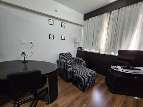 a living room with a table and a chair at Flat R. Maestro Cardim Benef Portuguesa (Apto 110) in Sao Paulo