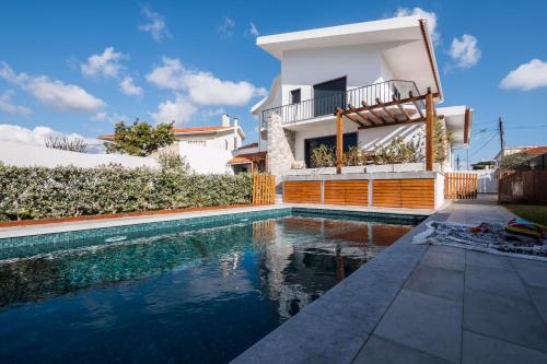 a villa with a swimming pool in front of a house at BeGuest Sun & Pool House in Parede