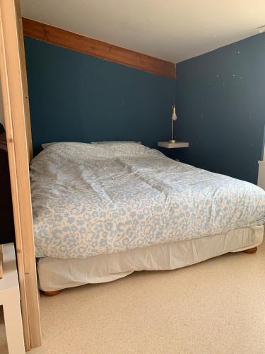une chambre avec un lit avec un mur bleu dans l'établissement Appartement charmant face au haras, à Saint Lo