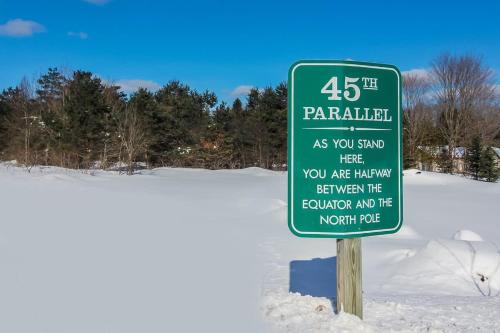 a green sign in the snow next to a road at #146 Golf, SkI, Pool Pass Walk to hill in Mancelona