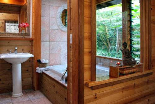 a bathroom with a bath tub and a sink at Lotus Garden Cottages in Volcano