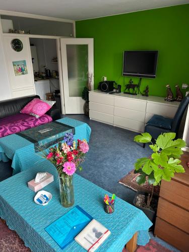 a living room with a couch and a table with flowers at B&B Calypso Amsterdam Shared Apartment in Amsterdam