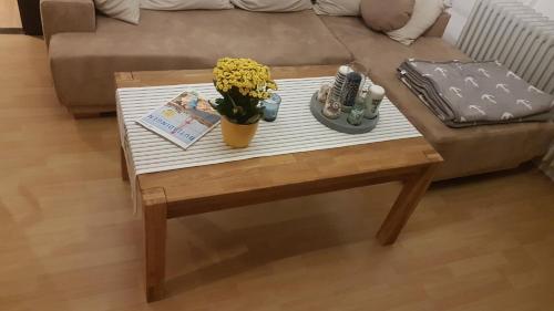 a coffee table with a vase of flowers on it at Ferienwohnung Conny in Butjadingen