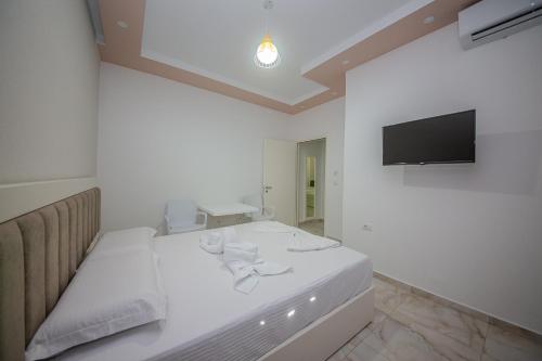 a white room with a bed and a flat screen tv at Hotel Landi in Ksamil