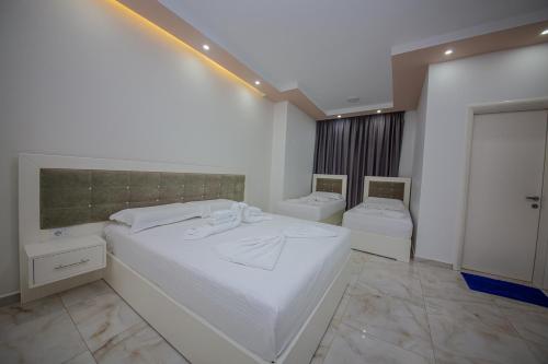 a bedroom with a large white bed and two toilets at Hotel Landi in Ksamil