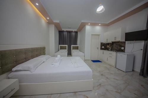 a bedroom with a large white bed and a kitchen at Hotel Landi in Ksamil