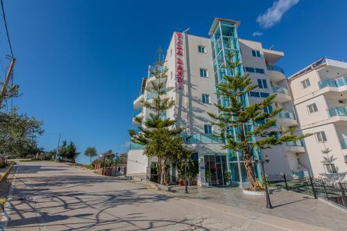 a tall white building with trees in front of it at Hotel Landi in Ksamil