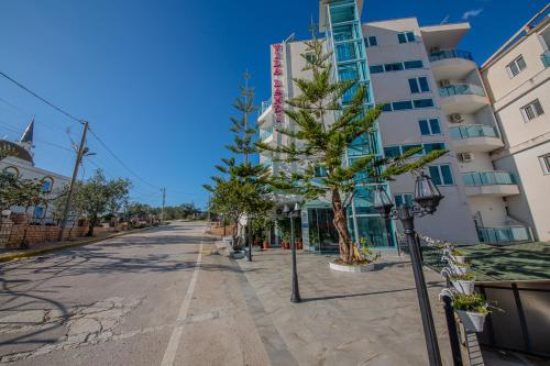 an empty street with palm trees in front of a building at Hotel Landi in Ksamil