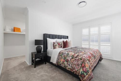 a white bedroom with a bed and a night stand at Parkview for 8, Moss Vale, Southern Highlands in Moss Vale
