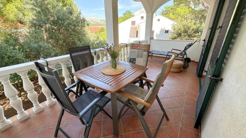 eine Veranda mit einem Holztisch und Stühlen auf dem Balkon in der Unterkunft Rose Wind Apartments by Pag tours in Pag