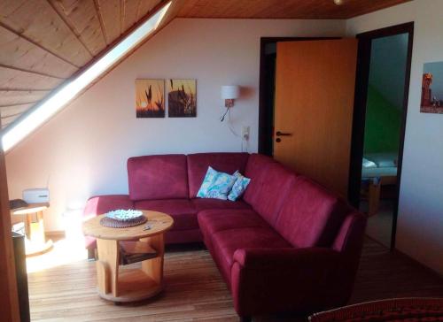 Una sala de estar con un sofá rojo y una mesa. en Ferienwohnung Baumgarn, en Fehmarn