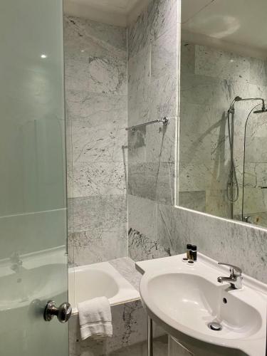 a white bathroom with a sink and a shower at Art Hotel Athens in Athens