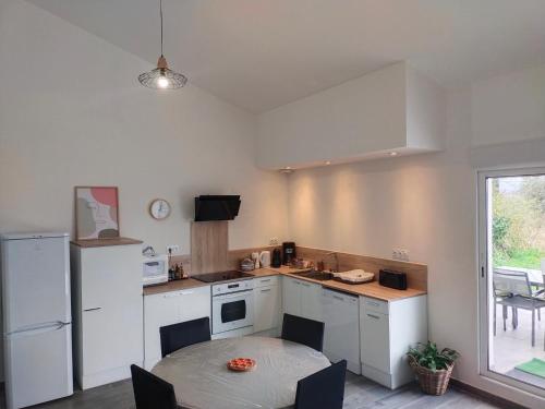 une cuisine avec une table et une petite cuisine avec des appareils blancs dans l'établissement Maison de village, à Lasbordes