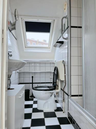 a bathroom with a toilet with a black and white checkered floor at Leoicom in Zandvoort