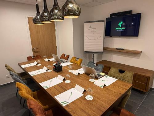 a conference room with a large wooden table with two laptops at Holiday Inn Dijon Sud - Longvic by IHG in Dijon